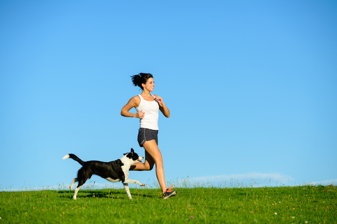Sporty happy woman running with dog outdoor