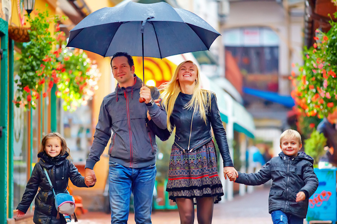 happy family walking under the rain on colorful street