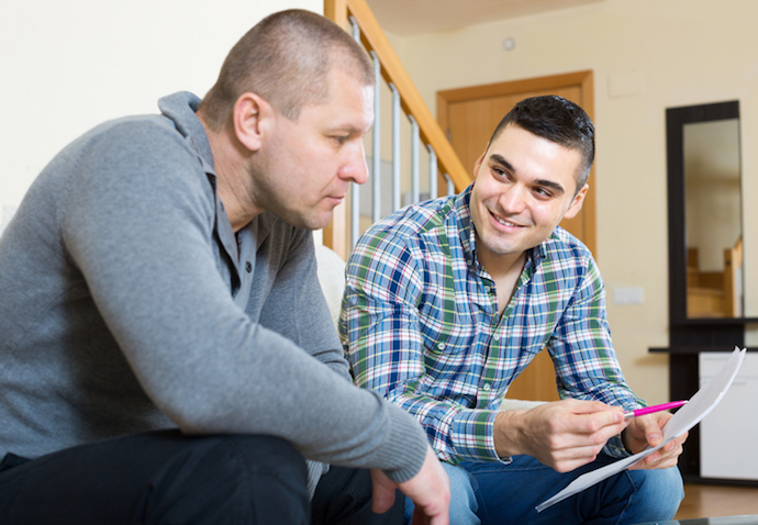 Man helping friend to fill document indoor