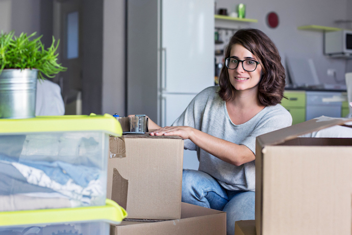 Woman packing cardboard boxes for moving home.