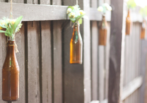 Empty bottles used as outdoor decoration, strung along the fence - a home for cute fake flowers!