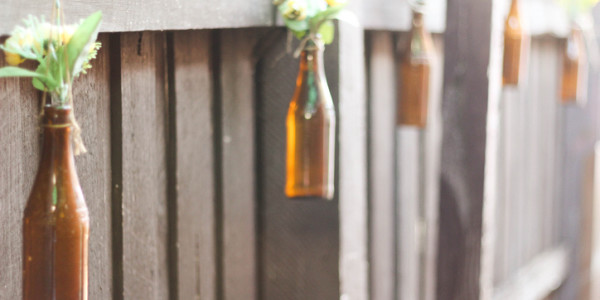 Empty bottles used as outdoor decoration, strung along the fence - a home for cute fake flowers!