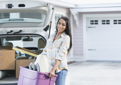 A young mixed race woman loading boxes of household items into the back of her car. She could be a new homeowner, or a college student  moving out to live in the dorms.