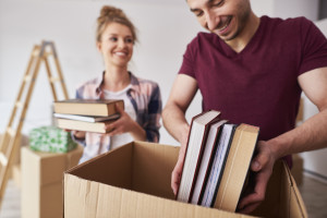 young couple packing books into moving boxes