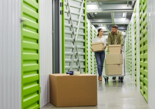 man and woman moving boxes on cart to a storage unit
