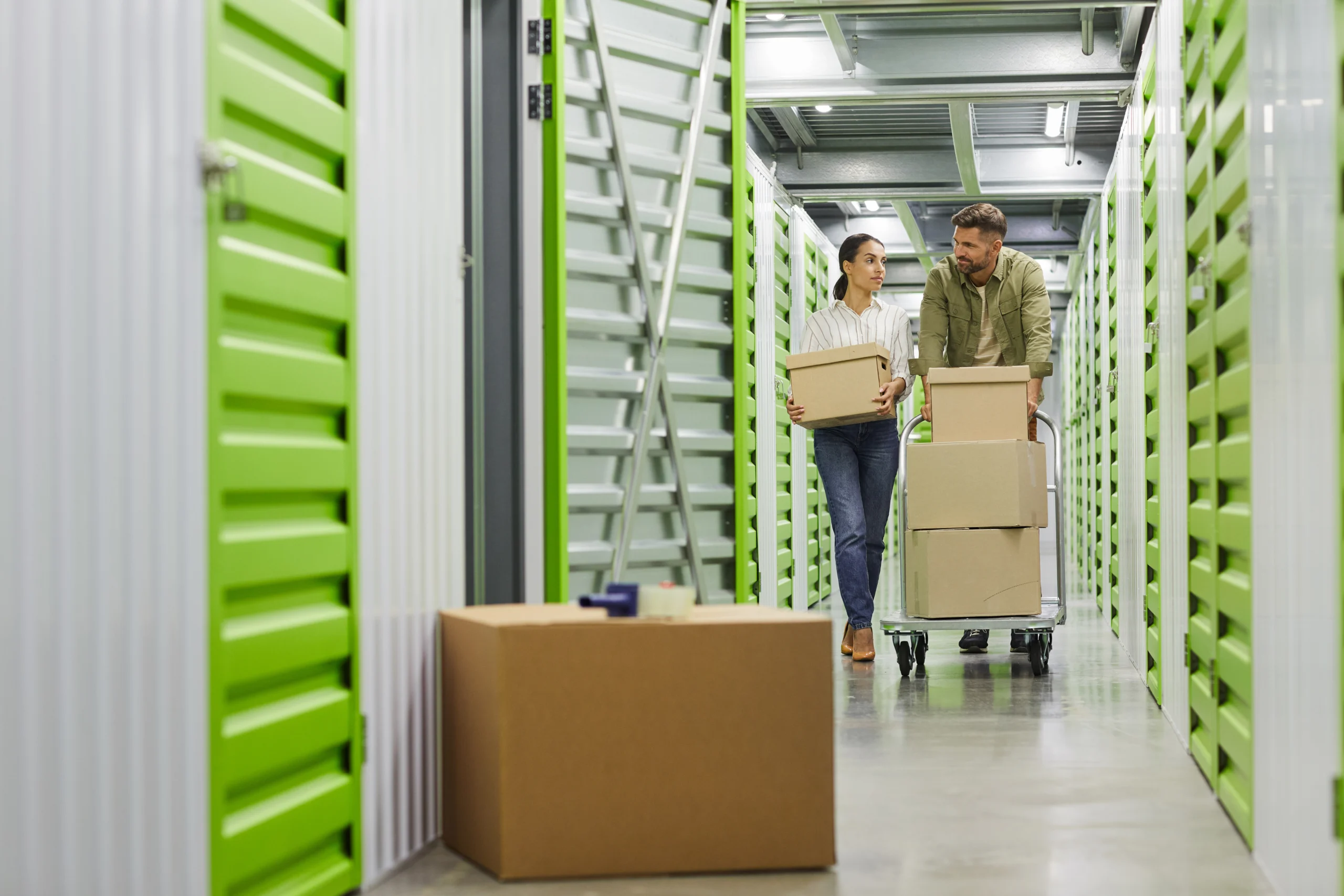 man and woman moving boxes on cart to a storage unit
