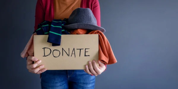 Donation concept. Woman holding donation box with clothes