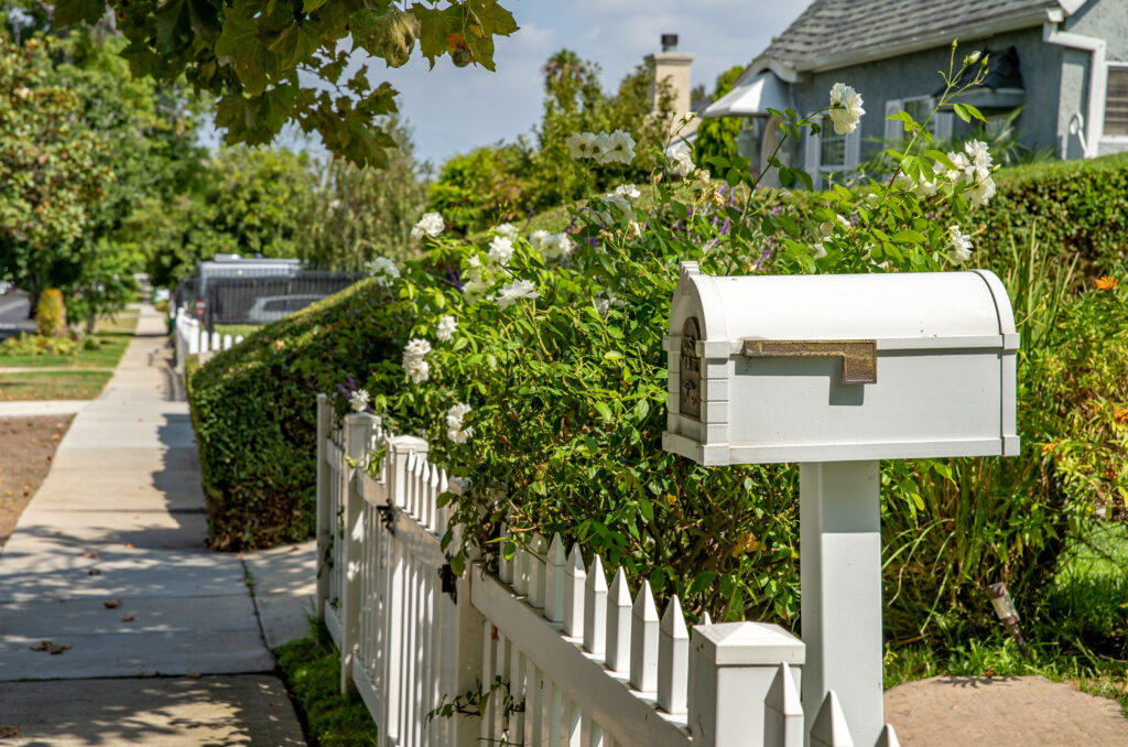 a white mailbox by the fence in front of a house