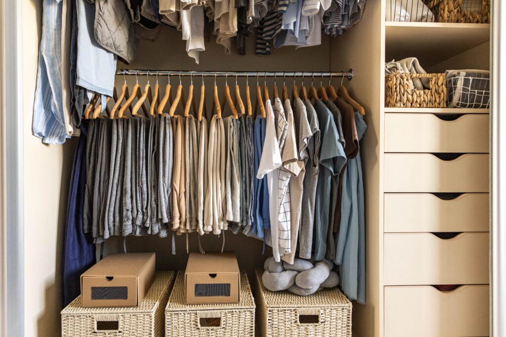 a closet with a double rod hanging system and storage boxes